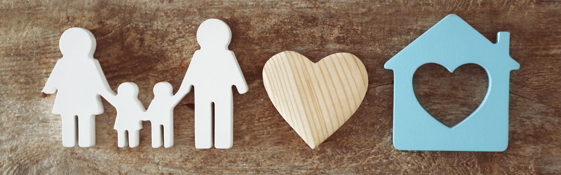 Photo de personnage illustrant une famille, un coeur et une maison sur un fond texturé de bois